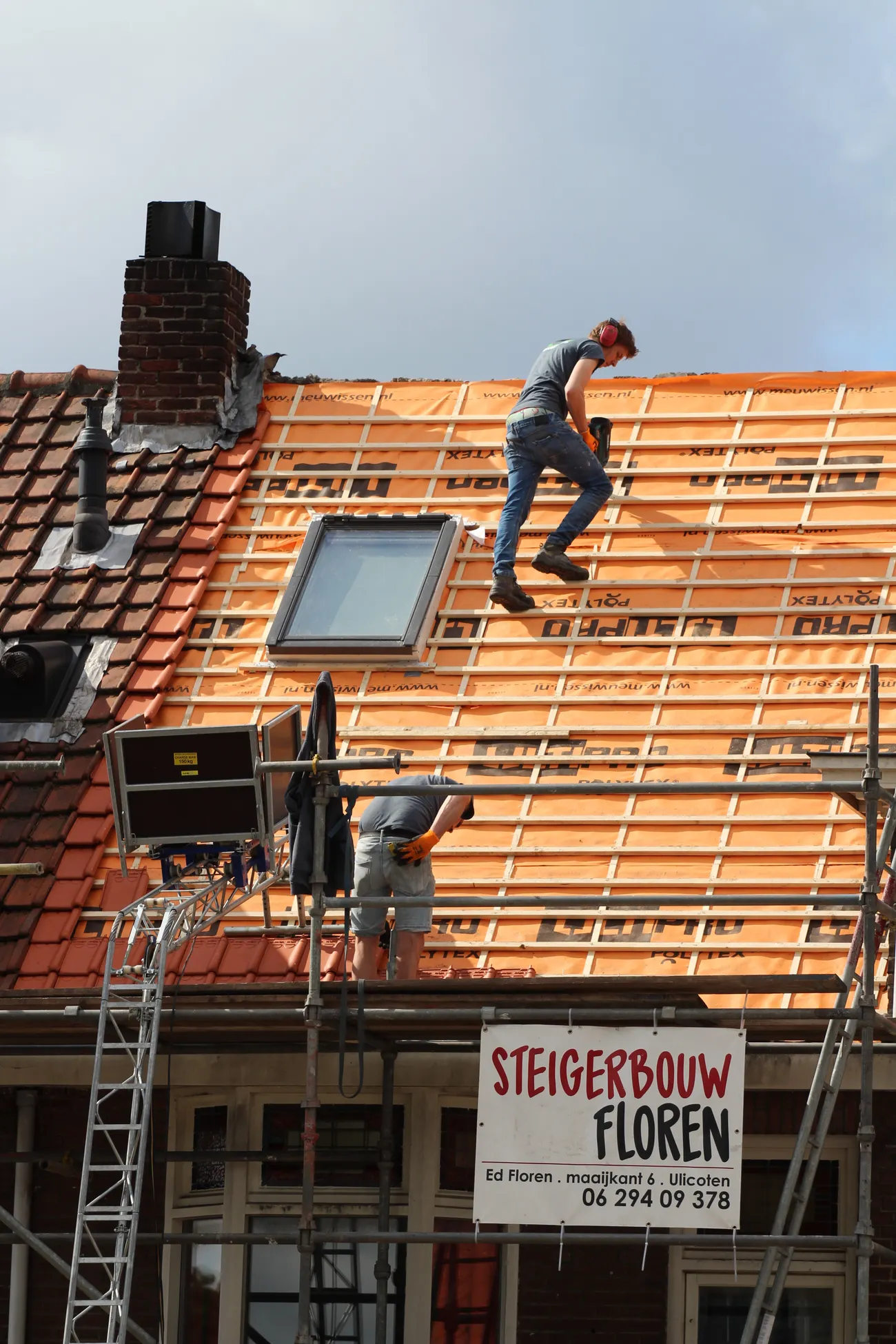 Workers installing roof tiles on a building